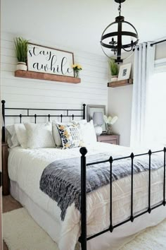 a bedroom with white walls and black iron bed frame, hanging planters on the wall