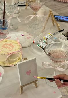 a table topped with lots of different types of cakes and glasses filled with watercolor paints