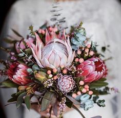 a bridal bouquet with pink flowers and greenery on the bride's dress