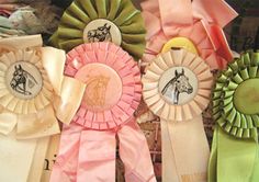 several ribbons with horses on them are lined up against a brick wall and one is pink, the other green