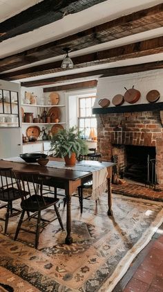 Cozy kitchen with exposed beams, brick fireplace, wooden dining table, and copper pots. Rustic and inviting space perfect for family gatherings. Log Cabin Dining Room Ideas, Brick Fireplace In Kitchen, Dining Room With Brick Fireplace, Dinning Room With Fireplace, Log Cabin Dining Room, Fireplace In Dining Room, Cabin Dining Room, Kitchen Hearth, Fireplace Dining Room