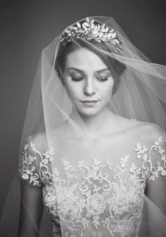 a black and white photo of a woman wearing a wedding dress with a veil over her head