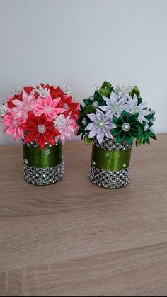 two vases filled with flowers sitting on top of a wooden table next to each other