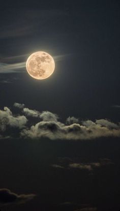 the full moon shines brightly in the night sky above some clouds and dark blue skies