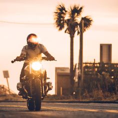 a man riding a motorcycle down a street with palm trees in the backgroud