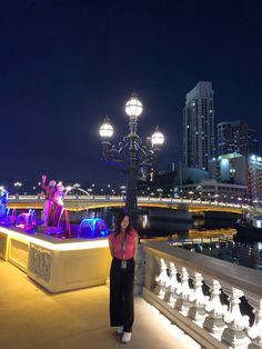 a woman standing on the edge of a bridge at night