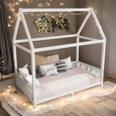 a white day bed sitting on top of a wooden floor next to a christmas tree