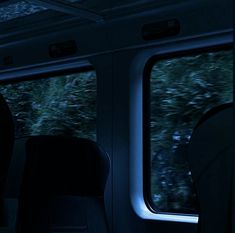 an empty train car with the lights on and trees in the backgrouund