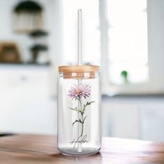 a glass jar with a flower painted on the side and a straw sticking out of it