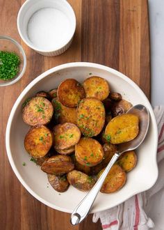 a white bowl filled with potatoes on top of a wooden cutting board