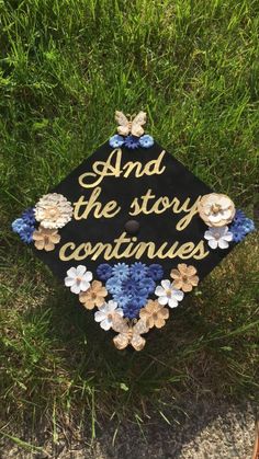 a graduation cap that says and the story continues with flowers on it sitting in the grass