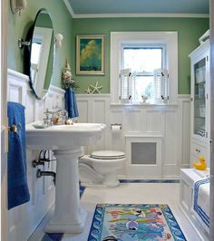 a bathroom with green walls and blue rugs on the floor next to a white toilet