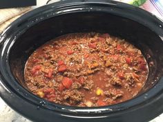 a crock pot filled with meat and vegetables on top of a table next to a napkin