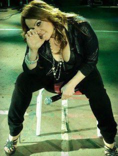 a woman sitting on top of a bench holding her hand up to her mouth and eating something