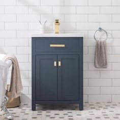 a bathroom with white tile and blue vanity cabinet next to the bathtub, towel rack and toilet