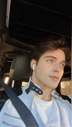 a man sitting in the back seat of a car with his headphones up to his ear