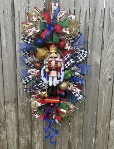 a christmas wreath hanging on the side of a wooden fence with ornaments around it and a nutcracker