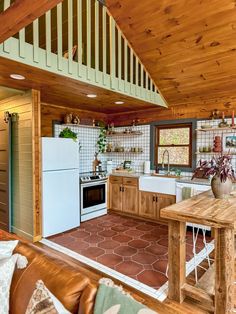 a kitchen and dining area in a cabin with wood ceilings, tile flooring and white appliances