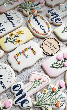 some decorated cookies are on a table with flowers and words in the middle one cookie has been cut out to look like letters