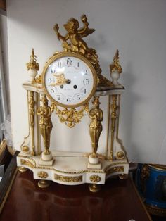 a gold and white clock sitting on top of a table