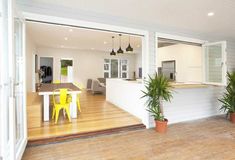 an open concept living room and dining area with wood flooring, white painted walls and wooden floors