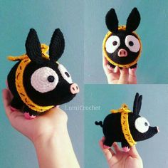 a hand holding a small black and yellow stuffed animal with two eyes on it's head