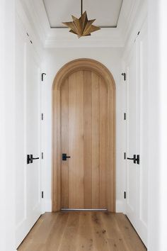 an empty hallway with a wooden door and light fixture above the entrance to another room