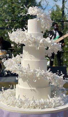 a wedding cake with white flowers on top is sitting on a table in front of a stage