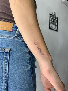 a woman's left arm with a small tattoo on her left wrist and the word love in cursive writing