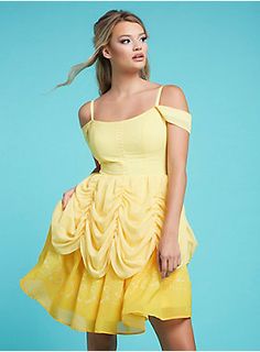 a woman in a yellow dress posing for the camera with her hair blowing in the wind