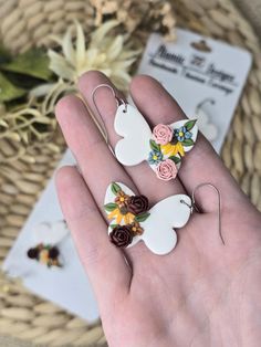 two white birds with flowers on them sitting in someone's hand