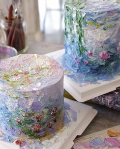 two colorful cakes sitting on top of white plates covered in frosting and flower designs