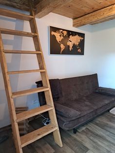 a living room with a brown couch and a wooden ladder next to the wall in front of it