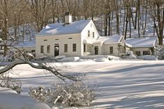 a white house surrounded by snow covered trees