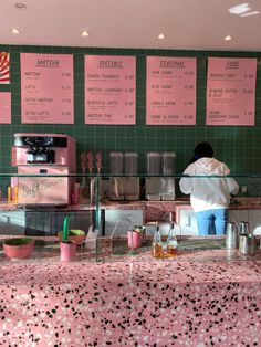 a person standing behind a counter in a restaurant with menus on the wall above it