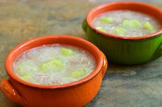 two orange bowls filled with soup sitting on top of a stone counter next to each other