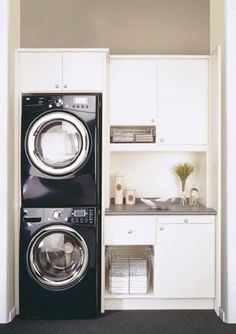 a washer and dryer in a small room with white cabinets on the walls