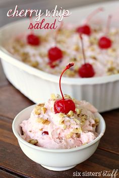 two bowls filled with ice cream and cherries next to each other on top of a wooden table