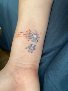 a person with a tattoo on their arm and the wrist has colorful paint splatters all over it