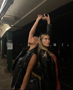 two women standing next to each other holding their hands in the air