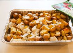 a pan filled with potatoes sitting on top of a table next to a green container