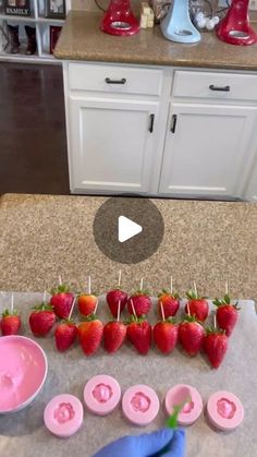 strawberries are arranged on toothpicks with pink icing