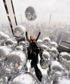 a woman sitting on top of a building surrounded by shiny balls