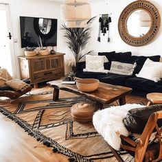 a living room filled with black couches and wooden tables in front of a mirror