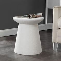 a white table sitting on top of a hard wood floor next to a beige chair