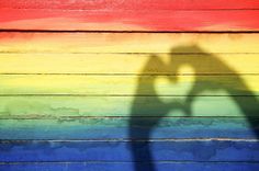 the shadow of a person's hand on a rainbow painted wooden wall