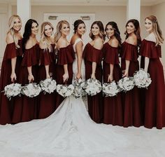 a group of women standing next to each other in front of a white door holding bouquets