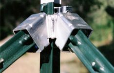 a close up of a metal object on a green pole with trees in the background