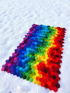 a multicolored rug is laying in the snow on top of some snow covered ground