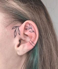 a woman's ear has a small leaf tattoo on it